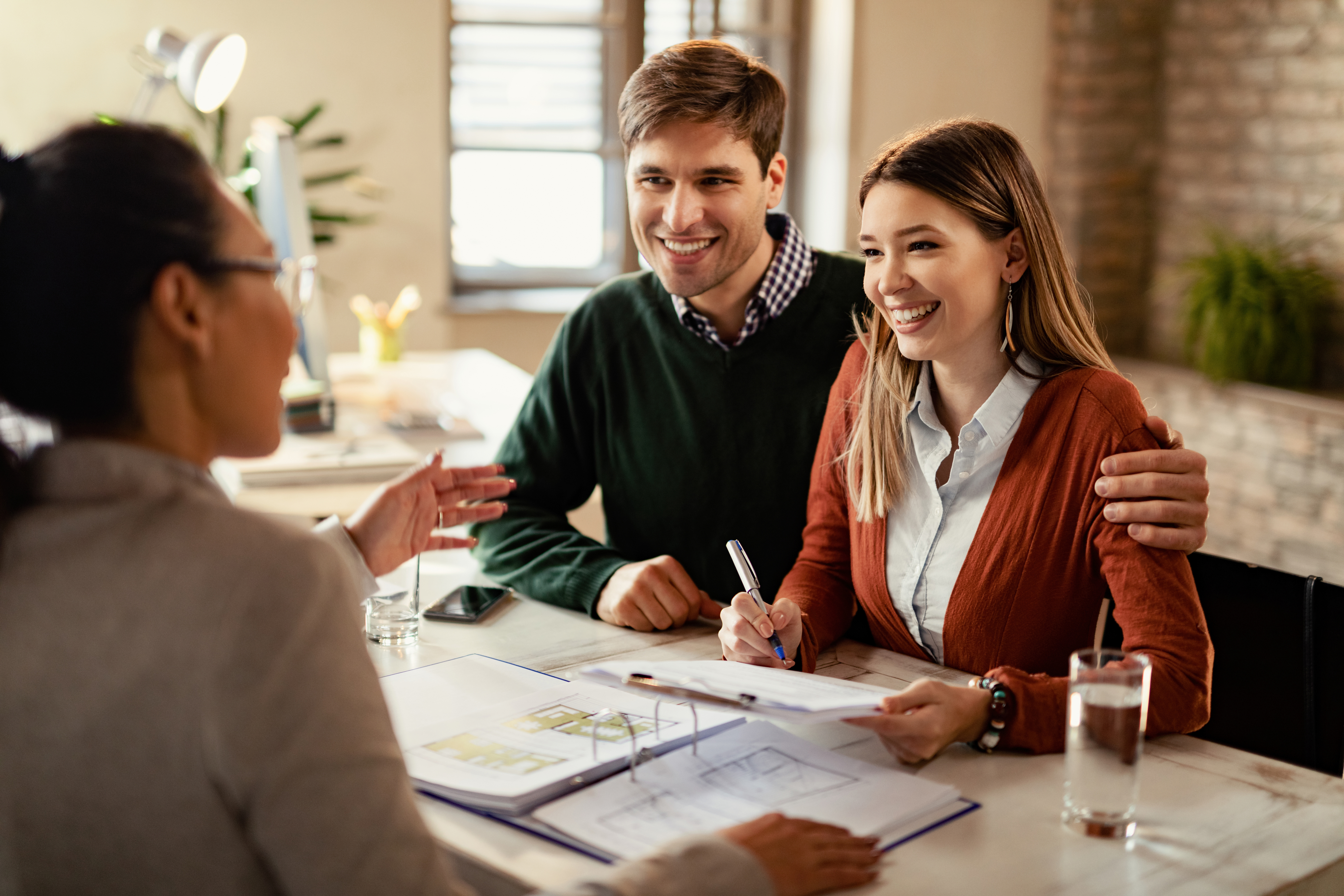 Young Happy Couple Signing Contract While Being Meeting With Insurance Agent Office